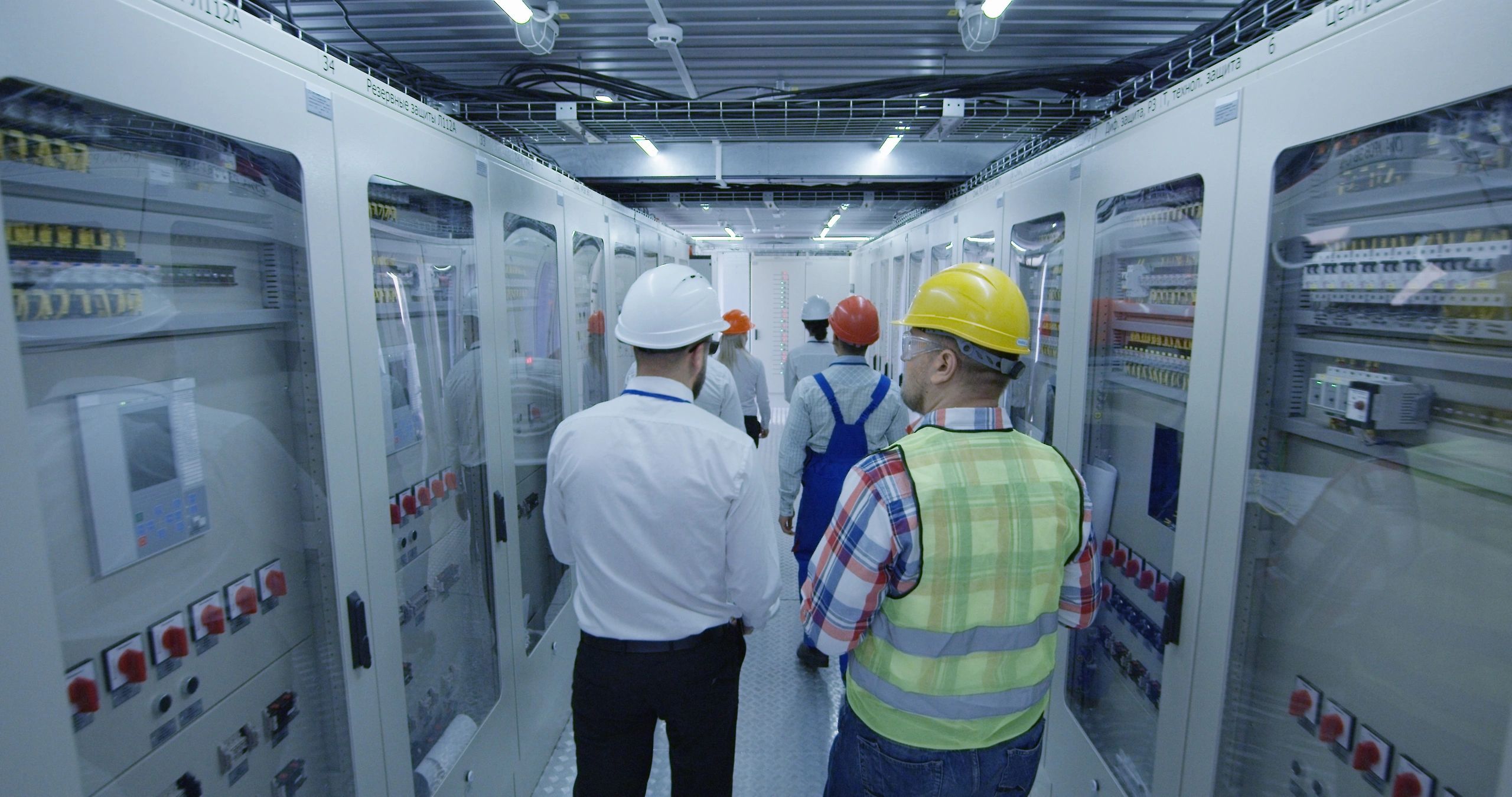 Electrical workers reviewing plans in a commercial control room